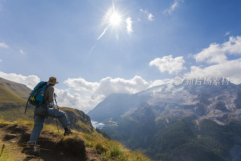 意大利北部Dolomites的Viel dal Pan小路上，一位老妇人正在欣赏美丽的Fedaia湖和Marmolada湖。